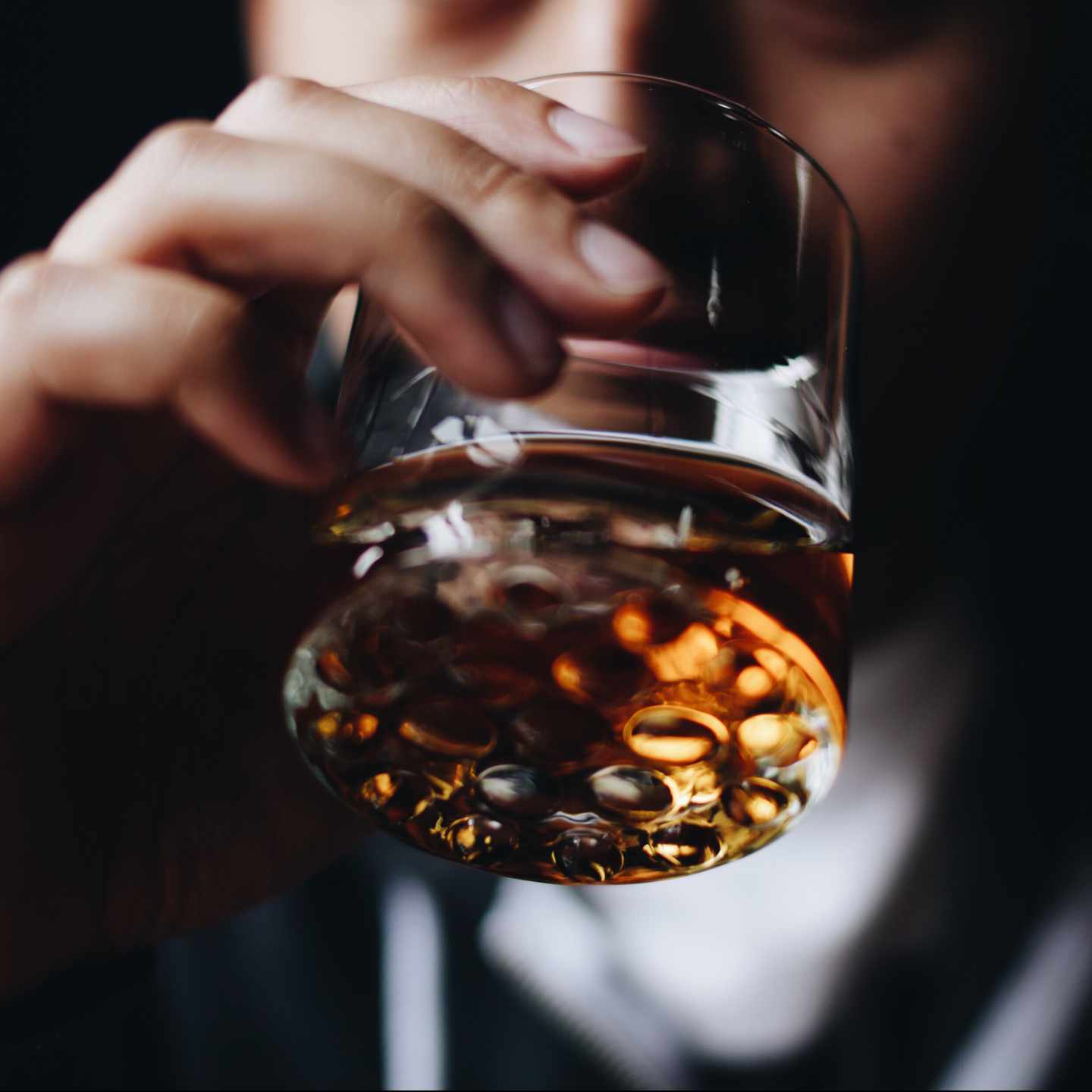 Close-up of glass of liquor being sipped.