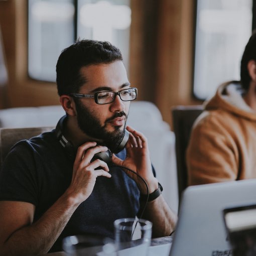 Casual Work Environment Male employee adjusting headphones while working on computer in office.