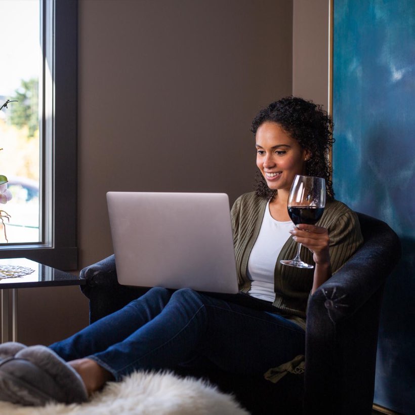 Women drinking wine and shopping on laptop.