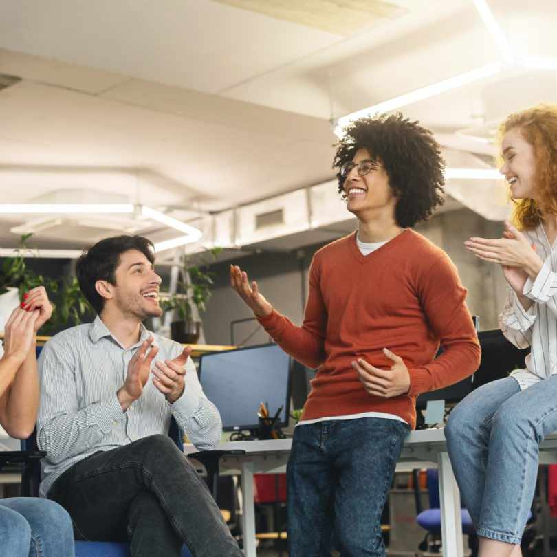 Co-workers laughing together in an office setting.